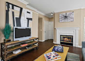 Thumbnail 4 of 25 - Spacious living room with wood-burning fireplace with glass doors, built-in shelves and hardwood floors at Tuscany Park Apartments in Houston.