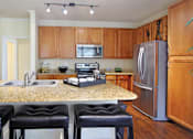 Thumbnail 18 of 37 - Luxury apartments in Houston with spacious kitchen and dining room with granite countertops, kitchen island, stainless steel appliances, oversized windows, lots of natural light, and hardwood floors.