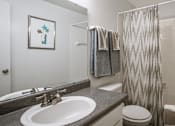 Thumbnail 19 of 42 - Spacious bright white bathroom with extra cabinet and storage space at Woodlake on the Bayou Apartments in Houston.