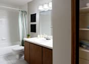 Thumbnail 7 of 30 - Spacious bathroom with lots of cabinet space, tiled floor, tiled shower, extra cabinet space, and gray wall color at The Vanderbilt Apartments in Omaha, Nebraska