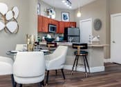 Thumbnail 6 of 29 - Luxury apartments with granite countertops, stainless appliances, large kitchen island, and dining room area at Delante apartments in Irving Texas