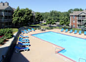 Thumbnail 5 of 44 - Apartments in Lincoln, Nebraska with two swimming pools, scenic views, lots of trees, poolside lounge chairs, and extra large sundeck
