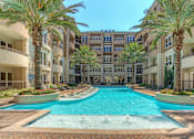 Thumbnail 5 of 42 - Luxury apartments with resort-style pool and palm trees, fountains, lap lane, and pool-side lounge chairs
