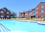Thumbnail 13 of 31 - Luxury apartments with red brick exteriors, swimming pool, pool-side lounge chairs, beautiful landscaping, and scenic views at Rockledge Oaks Apartments in Lincoln, Nebraska