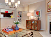 Thumbnail 23 of 36 - Spacious living room with wood-burning fireplace with glass doors, crown molding, and built-in bookshelves at Tuscany Apartments in Houston.