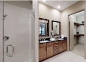 Thumbnail 27 of 42 - Luxury apartments with spacious master bathroom with oval soaking tub, separate shower with glass enclosure, and double sink with granite slab vanity top at Tuscany Walk Apartments in Houston.