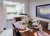 Thumbnail 20 of 38 - Spacious dining room with built-in bookshelf, bright kitchen with white cabinets, and breakfast bar at Woodlake Oaks Apartments in Houston
