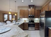 Thumbnail 28 of 42 - Luxury apartments with spacious kitchen and built-in wine rack, granite countertops, kitchen island, stainless steel appliances, and designer tile backsplash at Tuscany Walk Apartments in Houston Texas.