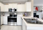 Thumbnail 16 of 31 - Luxury apartments with spacious u-shaped kitchen, white cabinets, stainless steel appliances, bright white kitchen at Rockledge Oaks Apartments in Lincoln, Nebraska