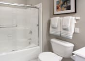 Thumbnail 21 of 31 - Luxury bathroom with tiled floors, glass shower, and oval soaking tub at Rockledge Oaks Apartments in Lincoln, Nebraska