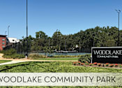 Thumbnail 10 of 42 - A sign for Woodlake Community Park is displayed in front of a building.