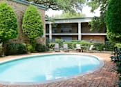 Thumbnail 17 of 19 - Apartments near the Galleria with multiple swimming pools, sun deck with poolside lounge chairs, brick exteriors and courtyard setting at Plantation apartments in Houston.