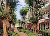 Thumbnail 22 of 36 - Luxury apartments with brick exteriors and lush landscaping including beautiful chaste trees at Tuscany Apartments in Houston.