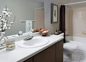 Thumbnail 16 of 30 - Spacious bathroom with lots of cabinet space, tiled floor, tiled shower, extra cabinet space, and gray wall color at The Vanderbilt Apartments in Omaha, Nebraska