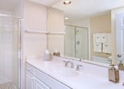 Thumbnail 8 of 41 - Bathroom with white cabinets, glass shower, extra cabinet space, walk-in shower, porcelain floor, and tiled shower at Embassy Park Apartments in Omaha, Nebraska