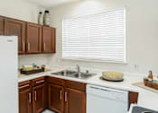 Thumbnail 30 of 36 - Spacious kitchen with honey brown toned cabinets with modern silver hardware, and white appliances including a double sided fridge with water and ice dispenser.