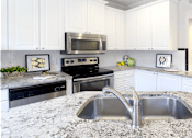 Thumbnail 3 of 34 - Spacious kitchen with island, granite countertops, custom home cabinets, French doors, smooth glass top stove, spacious pantries, breakfast bar and stainless-steel appliances at Tuscany Row Townhomes in Houston.