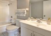 Thumbnail 7 of 10 - Bathroom with white cabinets, tiled floor, tiled shower with tub, and gray wall color at The Inverness Apartments in La Vista, Nebraska