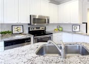 Thumbnail 9 of 26 - Spacious kitchen with island, granite countertops, white cabinets, smooth glass top stove, spacious pantries, breakfast bar and stainless-steel appliances at Tuscany Villas in Houston.