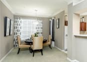 Thumbnail 26 of 36 - Spacious dining room and kitchen with honey brown toned cabinets with modern silver hardware, and white appliances.