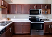 Thumbnail 3 of 40 - Spacious kitchen with stainless steel appliances and plank wood floors at Village on the Parkway Apartments