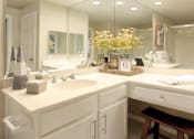 Thumbnail 18 of 22 - Spacious bathroom with oval soaking tub, glass shower, cultured marble vanity, and built-in vanity at The Dorchester Apartments in Houston.