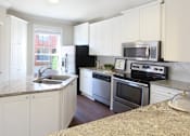 Thumbnail 17 of 34 - Spacious kitchen with island, granite countertops, custom home cabinets, French doors, smooth glass top stove, spacious pantries, breakfast bar and stainless-steel appliances at Tuscany Row Townhomes in Houston.