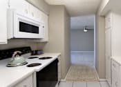 Thumbnail 5 of 10 - Bright white kitchen with gray wall color, white kitchen cabinets, lots of cabinet space, lots of counter space, spacious dining room and porcelain tile floors at The Inverness Apartments in La Vista, Nebraska