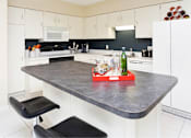 Thumbnail 24 of 41 - Large kitchen with lots of cabinet and counter space, white cabinets, colored feature wall, kitchen island, and prep island at Embassy Park Apartments in Omaha, Nebraska