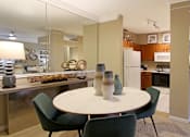 Thumbnail 15 of 22 - Dining room with mirror accent wall and U-shaped kitchen with breakfast bar at The Dorchester Apartments in north Dallas.