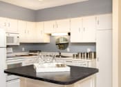 Thumbnail 10 of 41 - Kitchen with white cabinets, lots of cabinet space, kitchen island, prep island, and colored feature wall at Embassy Park Apartments in Omaha, Nebraska