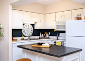 Thumbnail 3 of 41 - Kitchen with white cabinets, lots of cabinet space, kitchen island, prep island, and colored feature wall at Embassy Park Apartments in Omaha, Nebraska