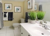 Thumbnail 10 of 27 - Spacious bathroom with white cabinets, tile floor and tiled shower with tub at Alpine Village Apartments in La Vista, Nebraska