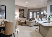 Thumbnail 50 of 62 - A view of an open living space with a dining nook on the left, kitchen counter on the right, and living area in the front. White furnishing on porcelain floor.