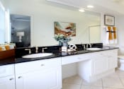 Thumbnail 4 of 34 - Spacious master bathroom with granite countertops, double sink vanity, double mirror vanity, and oval soaking tubs with glass enclosures at Tuscany Row Townhomes in Houston.