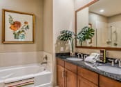 Thumbnail 11 of 36 - Luxury bathroom with granite countertops, glass shower and separate soaking tub at Villa Piana Apartments in Dallas