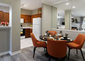 Thumbnail 15 of 36 - Luxury apartments with wood grain plank floors, dining room, u-shaped kitchen, mirror accent wall, and breakfast bar at Lenox Village Apartments in Lincoln, Nebraska