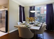 Thumbnail 34 of 73 - Spacious dining room with wood plank floors, oversized windows, kitchen with white cabinets, stainless-steel appliances, and side-by-side refrigerator at The Saxony Apartments