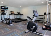 Thumbnail 7 of 27 - A gym with a treadmill, elliptical trainer, and other exercise equipment.