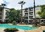 Thumbnail 26 of 37 - Luxury swimming pool with cabanas, poolside lounges, grilling stations, palm trees and beautiful landscaping at The Voss Apartments in Houston.