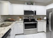 Thumbnail 3 of 38 - Luxury apartments with granite countertops, white cabinets, stainless steel appliances, and side-by-side refrigerator at TurtleCreek apartments in West Des Moines, Iowa
