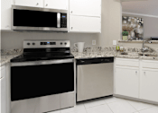 Thumbnail 24 of 35 - Spacious kitchen with white cabinets, granite countertops, stainless steel appliances, serving bar, and porcelain tile floors at Breckenridge Apartments in southwest Omaha, Nebraska