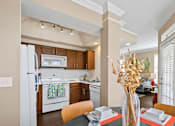 Thumbnail 18 of 25 - Spacious kitchen with custom home cabinets, side-by-side refrigerator, spacious dining room, and crown molding at Tuscany Park Apartments in Houston.