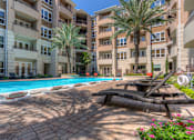 Thumbnail 29 of 42 - Luxury apartments with resort-style pool and palm trees, fountains, lap lane, and pool-side lounge chairs at Tuscany Walk Apartments in Houston