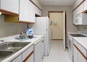Thumbnail 12 of 30 - Kitchen with lots of cabinet space, lots of counter space, gray wall color, and full-size washer and dryer at The Vanderbilt Apartments in Omaha, Nebraska