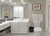 Thumbnail 5 of 42 - Spacious luxury bathroom with built-in cultured marble vanity, roman tub with glass shower, and porcelain tiled floor at The Biltmore Apartments in Omaha, Nebraska