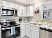 Thumbnail 17 of 73 - Luxury apartments with kitchens with white cabinets and stainless-steel appliances at The Saxony Apartments in Dallas