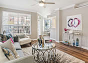 Thumbnail 20 of 73 - Spacious living room with wood plank floors, French door, and oversized windows at The Saxony Apartments in Dallas