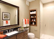Thumbnail 13 of 42 - Luxury bath suite with granite slab vanity top, frameless glass walk-in shower, and spacious linen cabinets and built-in shelves at Tuscany Walk Apartments in Houston.
