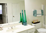 Thumbnail 28 of 36 - Spacious bathroom with oval soaking tub with glass enclosure, cultured marble vanity, and glass shower at Tuscany Apartments in Houston.